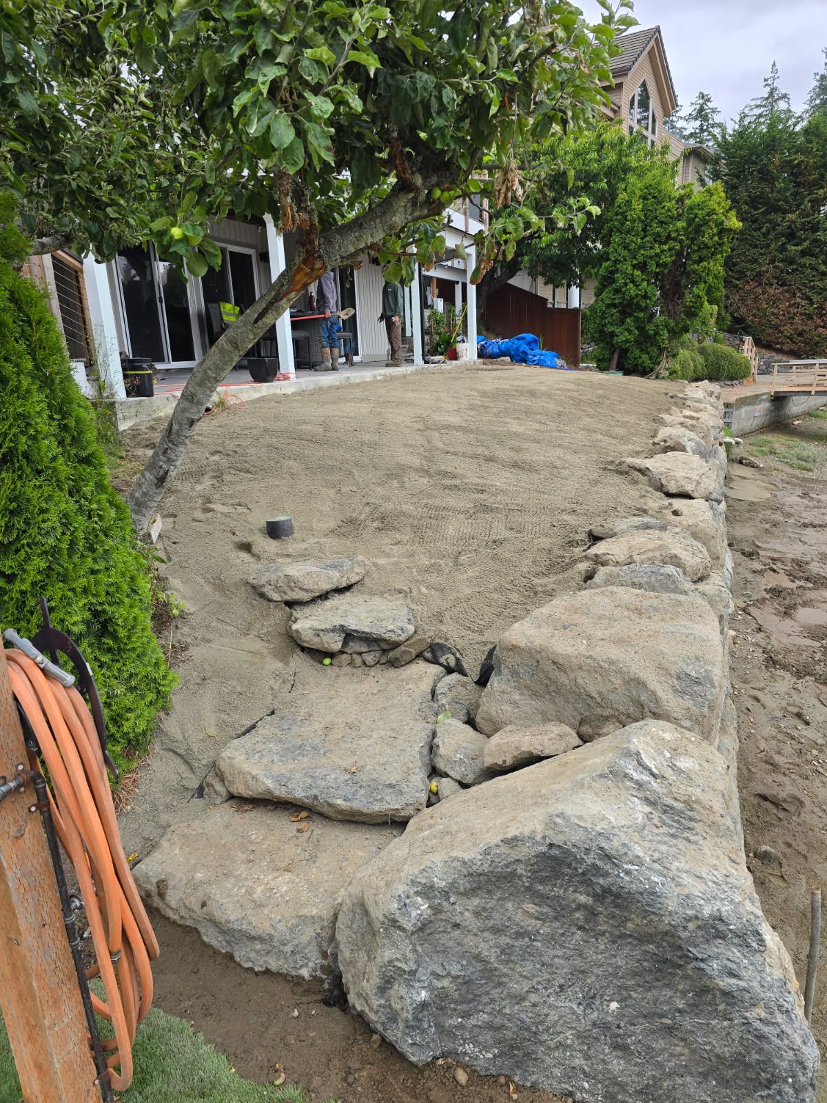 Residential backyard grading and landscape construction with boulder retaining features in the Puget Sound region